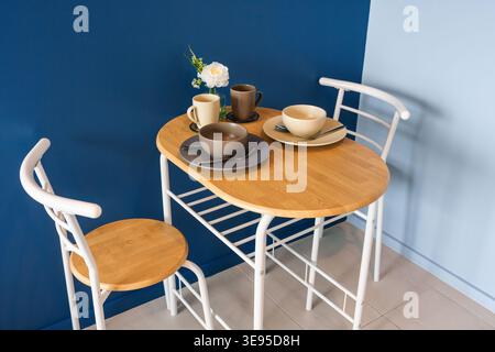 A stylish modern dining setup featuring a wooden table and ceramic dishware. Ideal for minimalistic and cozy kitchen environments. Perfect for any mea Stock Photo