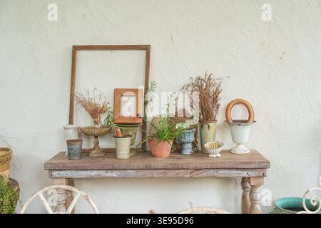Vintage antique object collection with vase, frame on wooden table and plaster wall in living room Stock Photo