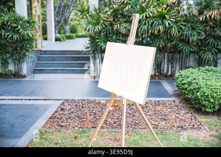 Empty white board canvas on wooden easel in the garden, Welcome sign, Mock up about wedding event Stock Photo