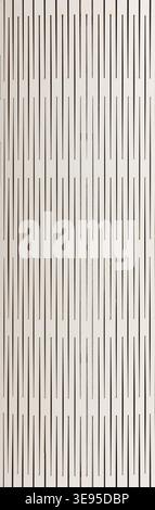 Full-frame, close-up view of a white or light beige paper or board surface featuring a pattern of thin, black, interrupted vertical lines or slots, cr Stock Photo