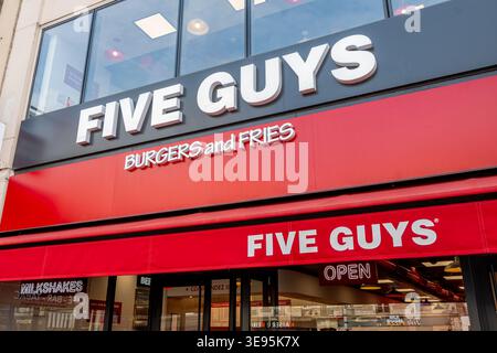 Signs and logo at the entrance of a Five Guys restaurant. Five Guys Enterprises, LLC is an American fast-food chain Stock Photo