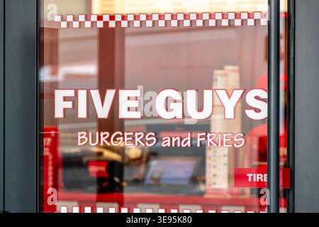 Sign and logo on the entrance door of a Five Guys restaurant. Five Guys Enterprises, LLC is an American fast-food chain Stock Photo