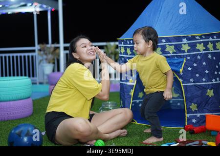 Mother and Son Giving a High Five Next to a Play Tent Stock Photo
