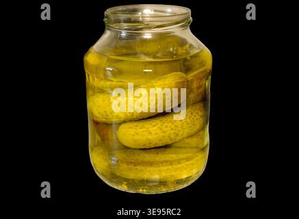 Detailed close-up of a glass jar filled with crunchy pickled cucumbers in a clear yellow brine. Authentic homemade preservation style with realistic glass reflections. Isolated on a transparent background for food design and packaging. jar of pickled cucumbers isolated on transparent background. Homemade preserved gherkins in brine, traditional canned food. High quality photo Stock Photo