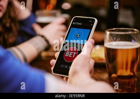 Adult Man Using Smartphone for Online Sports Betting in Bar Stock Photo