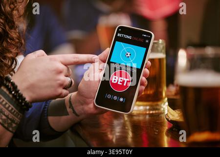 Adult Woman Using Smartphone for Online Sports Betting in Bar Stock Photo