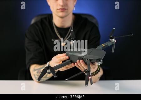 Young adult Caucasian man holding drone and presenting aerial filming equipment for content creation and streaming. Useful for technology marketing, creator economy, review blog visuals Stock Photo