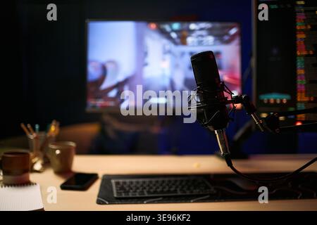Close up of podcast microphone standing beside keyboard and smartphone, supporting blogger streaming setup. Suitable for content creation, live broadcast, influencer marketing campaigns Stock Photo