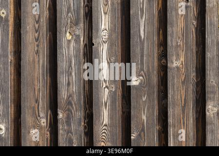 Weathered vertical wooden planks form a rustic fence wall with visible knots, pronounced grain and aged texture perfect as a natural background or arc Stock Photo
