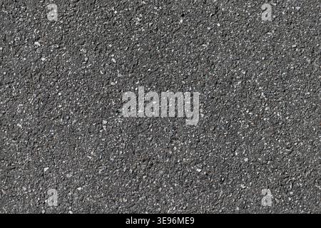 Close-up view of coarse asphalt pavement showing granular gravel, dark road surface and subtle texture suitable as a seamless background or overlay fo Stock Photo