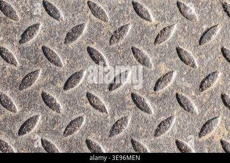Close-up of a metal diamond plate showing raised oval tread pattern on a weathered steel surface. Industrial, gritty texture ideal for backgrounds, de Stock Photo