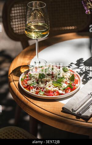 Mediterranean salad with wine on sunny table Stock Photo