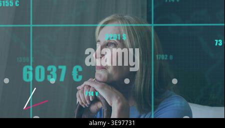 Mature woman resting chin atop cane at home, wearing blue top with teal financial overlay Stock Photo
