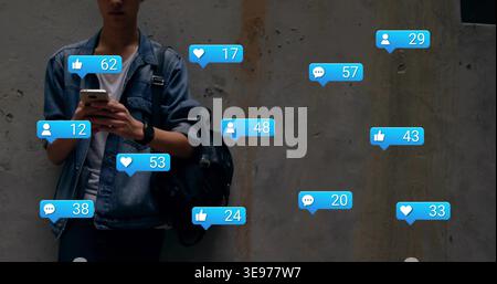 Denim-jacketed adult male leaning against wall in alley holding phone social bubbles, copy space Stock Photo