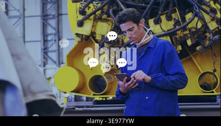 Technician wearing coverall checking tablet in factory, with yellow machine, mask and chat bubbles Stock Photo