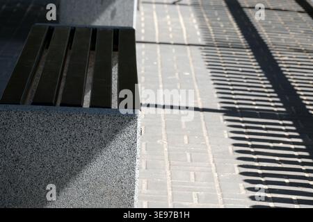 Soft light creates intriguing patterns on the bench and walkway in the park. Stock Photo