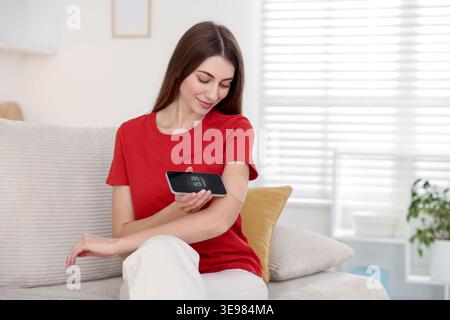 Diabetes. Woman with glucose sensor showing blood sugar level on smartphone at home Stock Photo