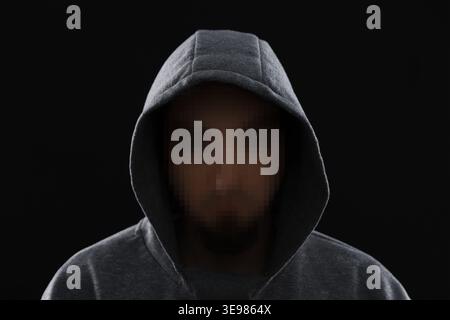 Anonymous man with pixelated face in hoodie on black background Stock Photo