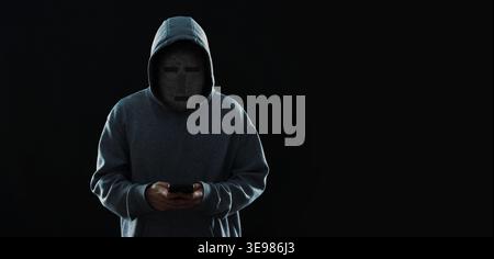 Anonymous man with pixelated face in hoodie on black background Stock Photo