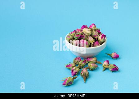 Dry Rose Buds, Roses Petals for Pink Flower Tea, Dried Persian Rosebuds, Rose Buds Textured Flowers Isolated on Blue Background Stock Photo