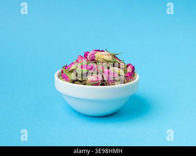 Dry Rose Buds, Roses Petals for Pink Flower Tea, Dried Persian Rosebuds, Rose Buds Textured Flowers Isolated on Blue Background Stock Photo