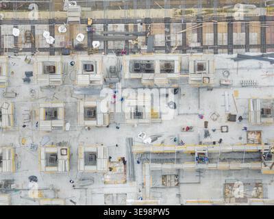 Aerial view of a top down construction site with workers, scaffolding, and concrete foundations in Taiwan. Stock Photo