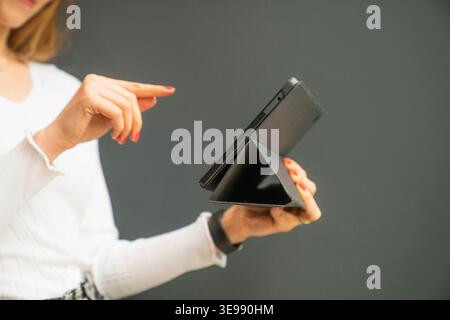 Close-up image of a woman holding and interacting with a foldable tablet device. Suitable for themes such as innovative technology, mobile devices, to Stock Photo