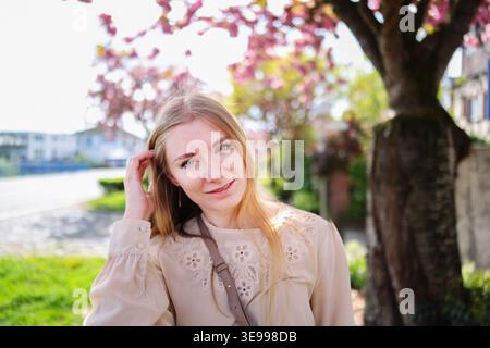 Spring portrait of woman among pink flowers, fresh air, light and joyful mood. Stock Photo
