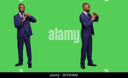 Company worker showing timeout pause gesture on camera posing over full body greenscreen. Young businessman expressing rejection and denial symbol, break sign in disagreement. Stock Photo