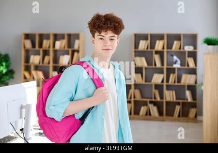 Confident teen student with backpack in bright library, ready for study and school Stock Photo