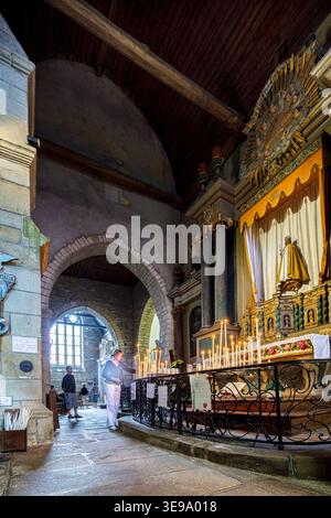 A devotee lights a votive candle to Our Lady of Tronchaye inside the Collegiate Church of Our Lady of Tronchaye in Rochefort-en-Terre, France. Stock Photo
