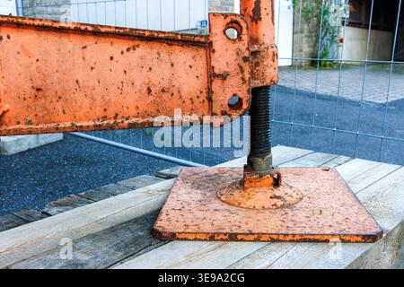 Rusty construction crane outrigger foot on pavement close up. Heavy machinery stability and safety. Stock Photo