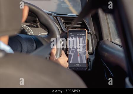 A car driver wearing a seat belt and using a GPS map navigation app on his smartphone Stock Photo