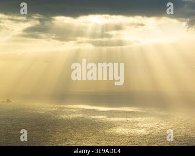 Aerial view of dramatic sunbeams breaking through dark clouds over the Atlantic Ocean near the coast of Madeira, Portugal. Stock Photo