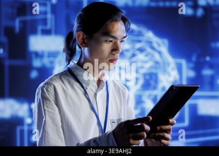 Computer scientist using tablet to maintenance artificial intelligence neural networks simulating human thought processes in computerized model. Tech support doing checkup on AI systems Stock Photo
