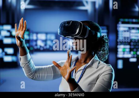 Trained technician in data center uses virtual reality to prevent system overload. Experienced VR headset user in server room ensuring enough network bandwidth for smooth operations Stock Photo