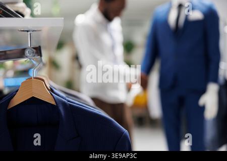 Apparel hanging on rack in shopping mall clothing section with blurred background. Male stylish jackets on hangers showcasing merchandise new collection in fashion boutique Stock Photo