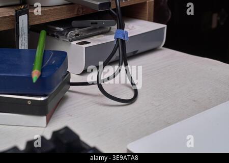 A white desk displays various storage devices, from stacked HDDs to a modern NVMe SSD. Cables and a green pencil complete this authentic IT workspace. Stock Photo