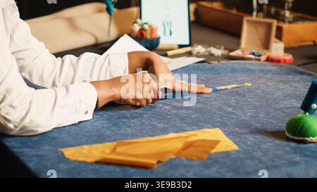 Young tailor using meter on fabric for custom made clothes collection, sewing industry. Female couturier doing measurements to make luxury design for clients. Handheld shot. Close up. Stock Photo