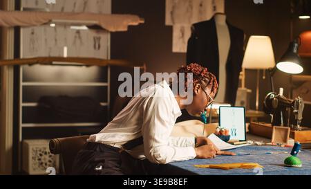 Atelier employee working with meter to prepare fabric for custom made clothing, tailoring concept. Seamstress doing measurement to create fashion design for clients, textile indutry. Handheld shot. Stock Photo