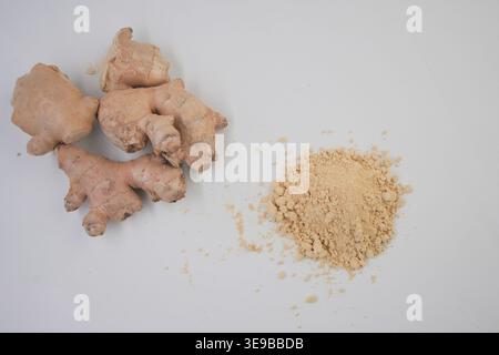 Ginger root and ginger powder displayed on a white surface Stock Photo