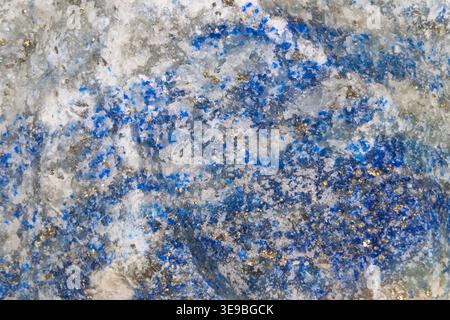Closeup blue crystalline matrix on grey host rock, scattered azure specks and metallic flecks create cosmic, celestial texture ideal for science visua Stock Photo