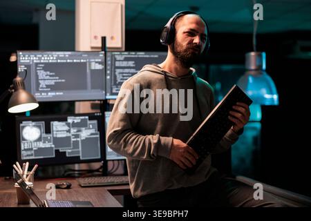 Cheerful developer fooling around with keyboard playing guitar, working on user interface with multiple screens parsing algorithm in software agency. Writing code and programming server. Stock Photo