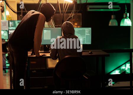 Hackers coding malicious software, cracking database password, online server illegal access, data breach. Cybercrime, internet thieves hacking computer network system at night time Stock Photo