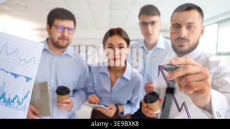Team of business analysts drawing on glass screen in office Stock Photo