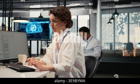 Stressed programmer in office listening music to relax while working with complex AI calculations. Fatigued IT employee putting audio headphones on, training deep learning systems, camera A Stock Photo