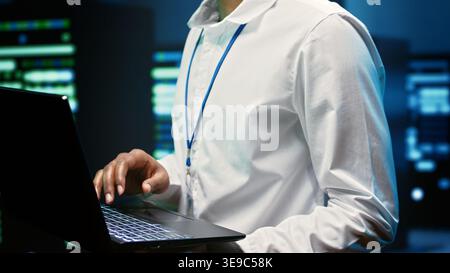Precise technician in high tech facility repairing network issues affecting server rigs performance and connectivity, leading to slow data transfer rates and poor client communication, close up Stock Photo