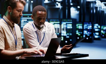 Teamworking experts doing maintenance on servers helping businesses manage databases, host websites and store files. Engineers monitoring supercomputers used for high performance computing Stock Photo