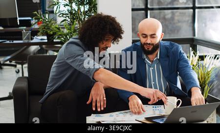 Team of workers plans analytics report, working on business collaboration in open space. Middle eastern colleagues discussing new development strategy and vision in startup office. Tripod shot. Stock Photo