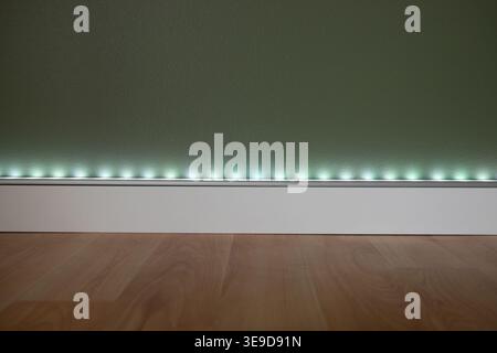 An LED lamp with an aluminium profile and a diffused plastic cover, mounted on the sage green color wall. Stock Photo